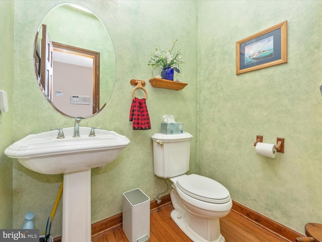 bathroom with baseboards, wood finished floors, and toilet