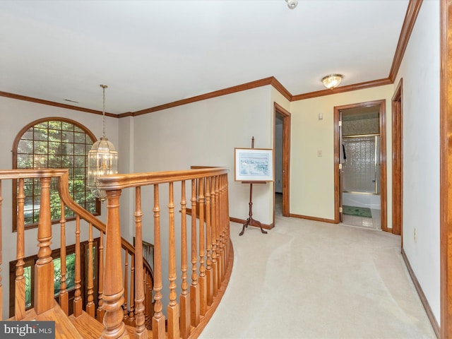 corridor with carpet flooring, an upstairs landing, a chandelier, baseboards, and ornamental molding
