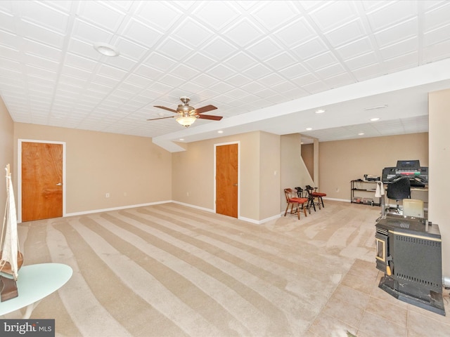 interior space with a wood stove, baseboards, light colored carpet, ceiling fan, and recessed lighting
