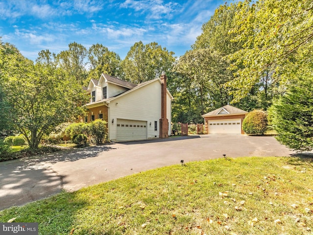 view of home's exterior with a lawn, an outbuilding, a chimney, and driveway
