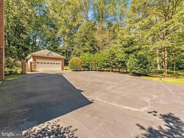 exterior space with brick siding, an outbuilding, driveway, and a garage