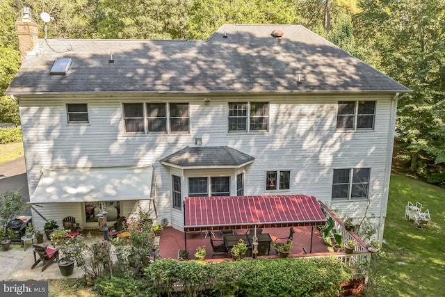 back of house featuring a lawn, a patio area, and a chimney