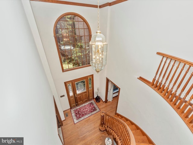 entryway with stairs, baseboards, a high ceiling, a notable chandelier, and wood finished floors