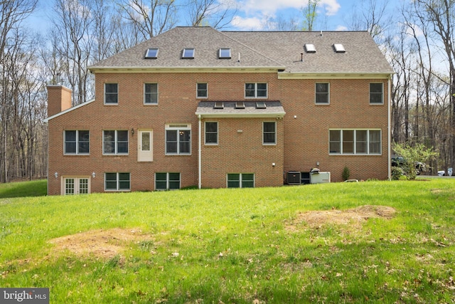 back of house with a yard, central air condition unit, brick siding, and a chimney