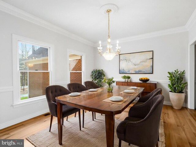 dining room featuring light wood-style flooring, baseboards, an inviting chandelier, and crown molding