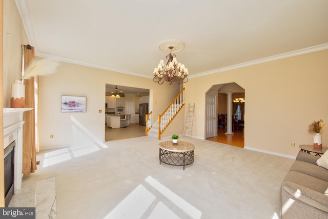living room featuring arched walkways, ornamental molding, carpet flooring, a chandelier, and a high end fireplace