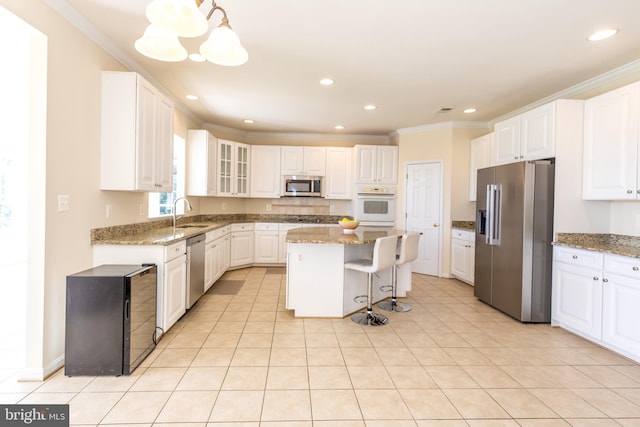 kitchen featuring appliances with stainless steel finishes, a sink, a center island, light stone counters, and recessed lighting