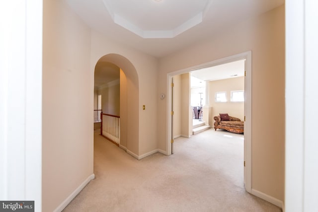 corridor with carpet flooring, arched walkways, and baseboards