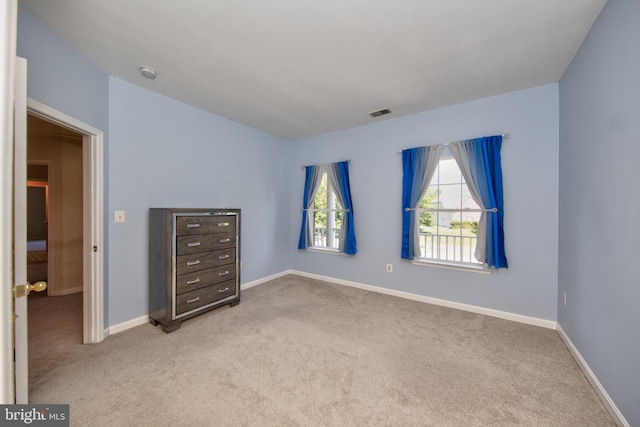 unfurnished bedroom featuring light carpet and baseboards