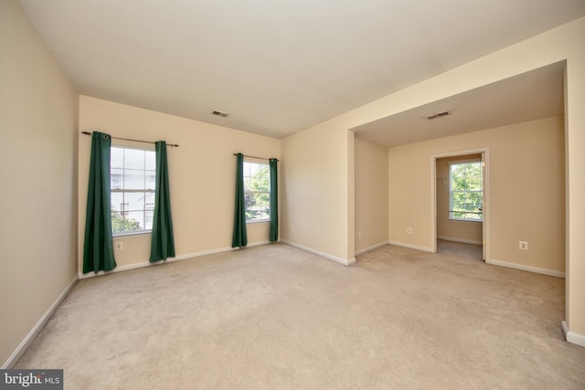 empty room featuring light carpet, healthy amount of natural light, and baseboards
