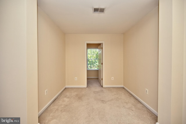 unfurnished room featuring light carpet and baseboards