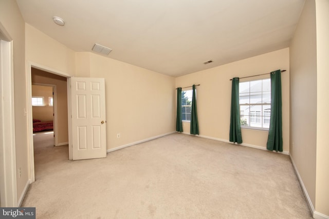 empty room featuring light colored carpet, plenty of natural light, a smoke detector, and baseboards