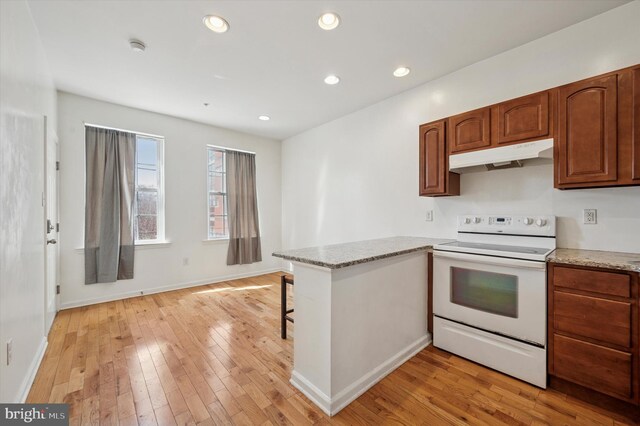 kitchen featuring light wood-style flooring, a peninsula, recessed lighting, under cabinet range hood, and electric range