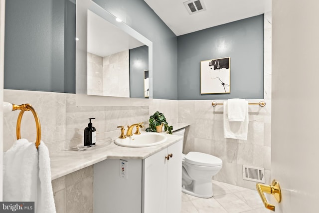 2646 S June St, Arlington, VA 22202 - bathroom with tile walls, toilet, vanity, marble look tiles, and a wainscoted wall