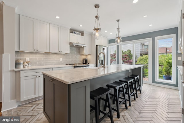 15 Chesapeake Lndg, Annapolis, MD 21403 - kitchen featuring stainless steel appliances, backsplash, under cabinet range hood, white cabinetry, and a kitchen island with sink