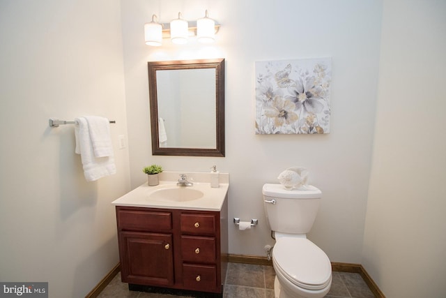 half bathroom featuring toilet, vanity, and baseboards
