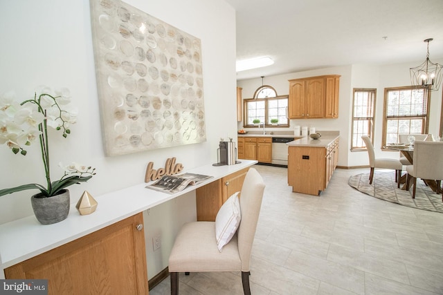 kitchen with dishwashing machine, light countertops, a sink, hanging light fixtures, and a notable chandelier