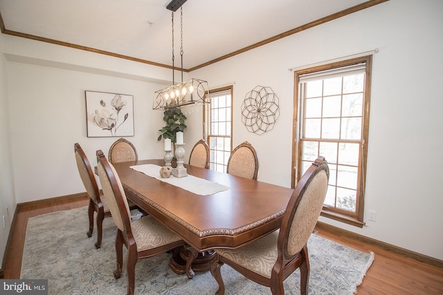dining room featuring a chandelier, baseboards, crown molding, and wood finished floors