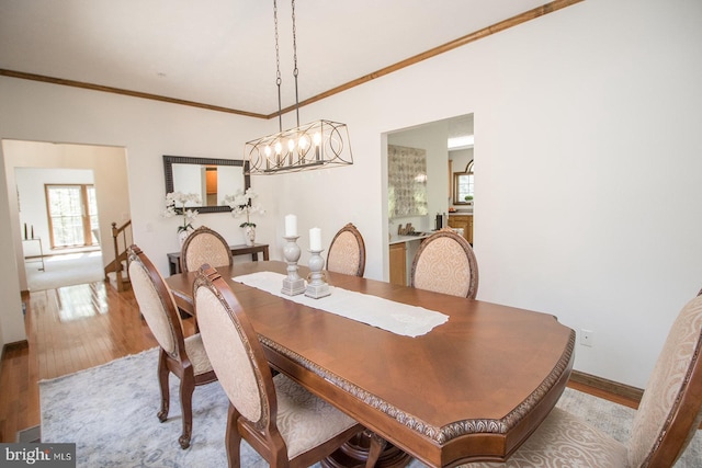 dining room featuring ornamental molding, baseboards, a notable chandelier, and wood finished floors