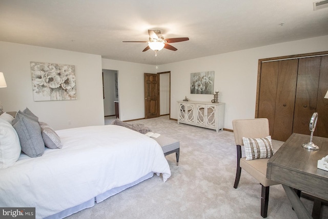 bedroom with a closet, baseboards, a ceiling fan, visible vents, and light colored carpet