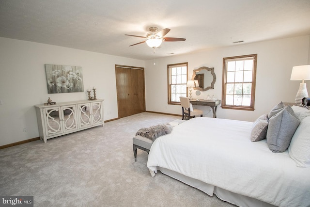 bedroom with ceiling fan, a closet, light colored carpet, visible vents, and baseboards