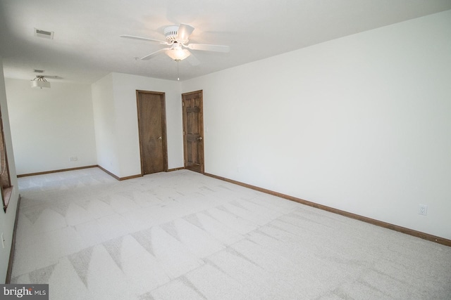 unfurnished room featuring visible vents, baseboards, a ceiling fan, and light colored carpet