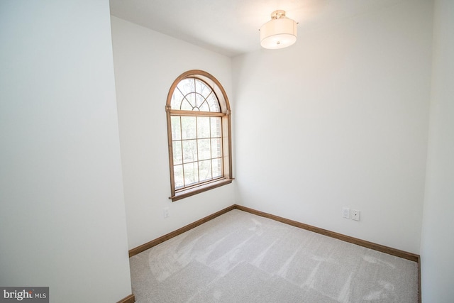 carpeted empty room featuring baseboards