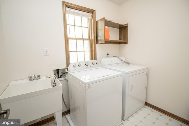 clothes washing area with laundry area, light floors, independent washer and dryer, a sink, and baseboards
