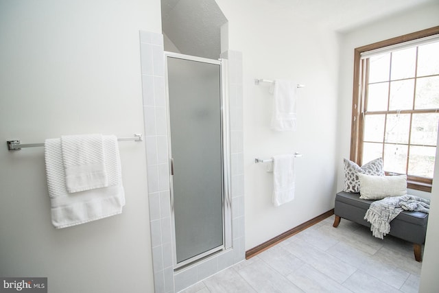 bathroom with a stall shower, ensuite bath, and baseboards