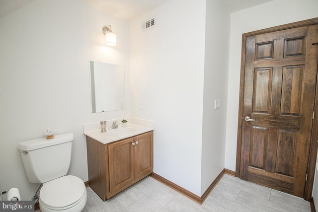 half bathroom with toilet, vanity, baseboards, and visible vents
