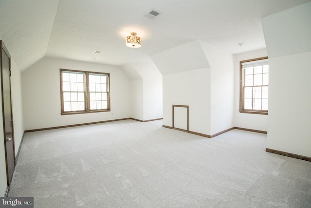 additional living space with visible vents, lofted ceiling, carpet floors, and a healthy amount of sunlight