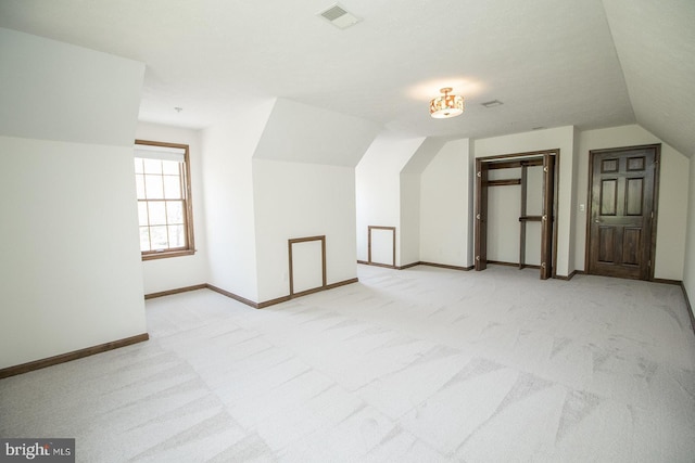 additional living space with light colored carpet, baseboards, vaulted ceiling, and visible vents