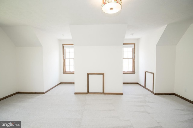 bonus room featuring light carpet, baseboards, lofted ceiling, and a wealth of natural light