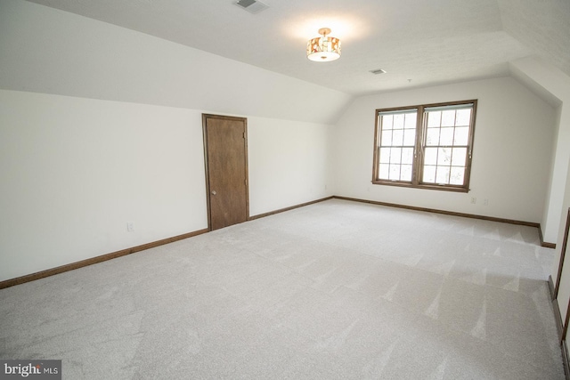 bonus room with vaulted ceiling, light colored carpet, baseboards, and visible vents