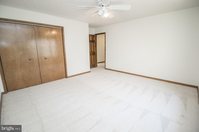 unfurnished bedroom featuring light carpet, a closet, baseboards, and a ceiling fan