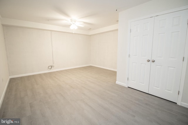 unfurnished bedroom featuring wood finished floors, a closet, and baseboards