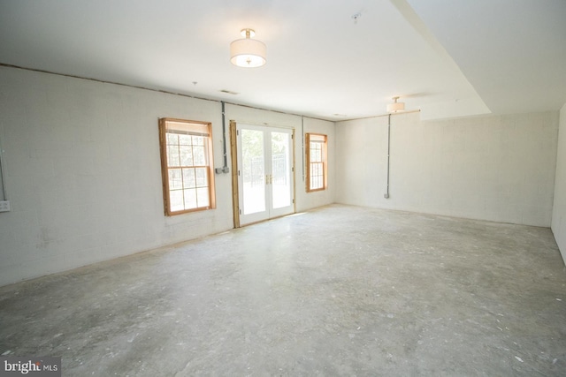 empty room with french doors, concrete flooring, and concrete block wall