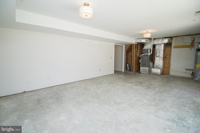 interior space with concrete flooring, heating unit, visible vents, and water heater