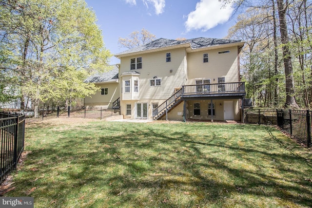 back of property with a fenced backyard, stairway, a deck, and a lawn