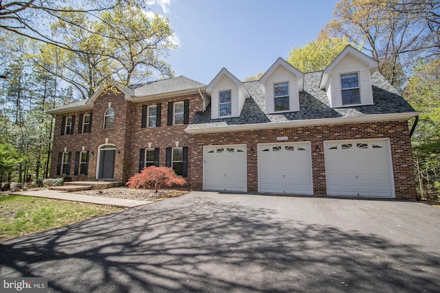 view of front of home with a shingled roof, brick siding, driveway, and an attached garage