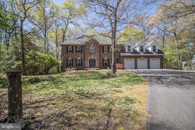 view of front facade with driveway, a front yard, and brick siding
