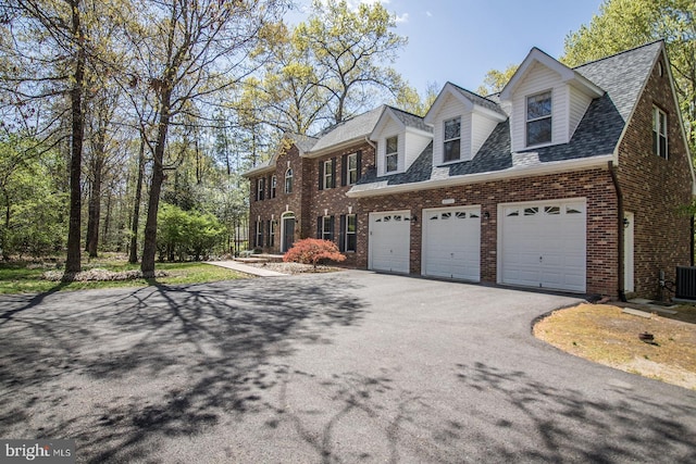 view of front facade featuring a garage, roof with shingles, brick siding, and driveway