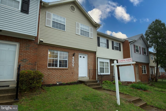 townhome / multi-family property with brick siding and a front yard