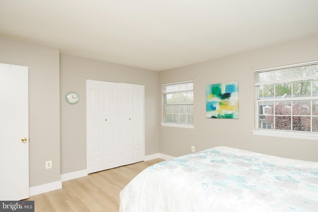 bedroom featuring light wood-style flooring, a closet, and baseboards