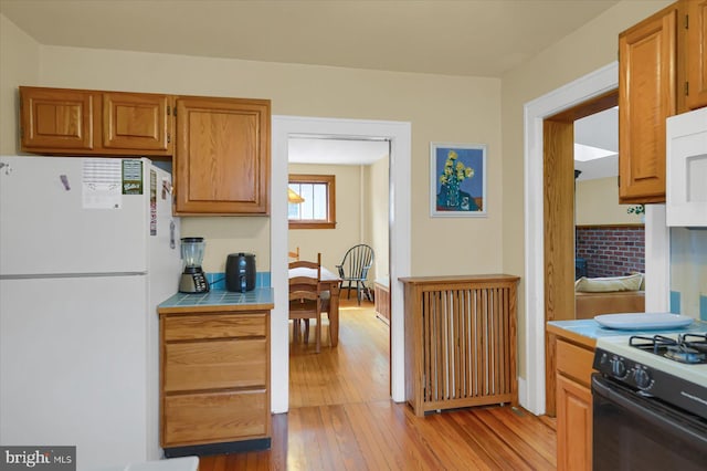 157 Hartswick Ave, State College, PA 16803 - kitchen featuring light wood-type flooring, white appliances, brown cabinets, and tile counters