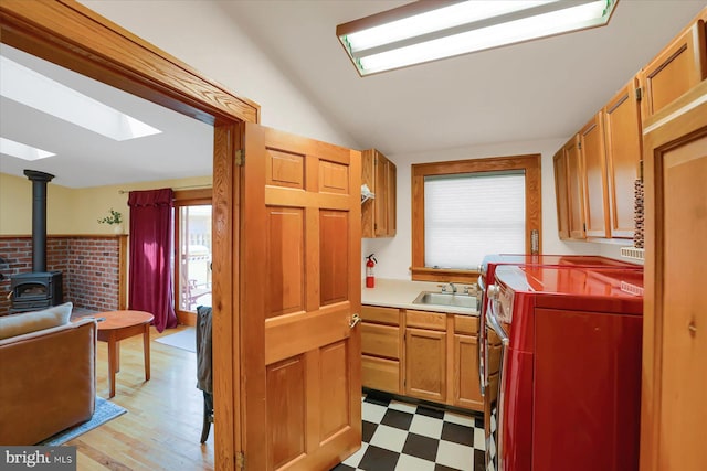 157 Hartswick Ave, State College, PA 16803 - kitchen featuring light floors, vaulted ceiling with skylight, a wood stove, separate washer and dryer, and a sink
