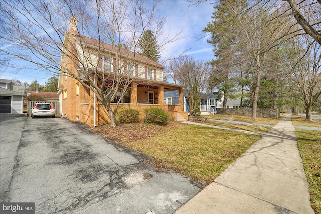 157 Hartswick Ave, State College, PA 16803 - view of front of home featuring brick siding, a front yard, covered porch, a chimney, and driveway