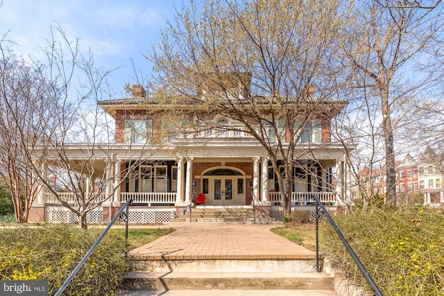 view of front of property featuring a porch, french doors, and a chimney