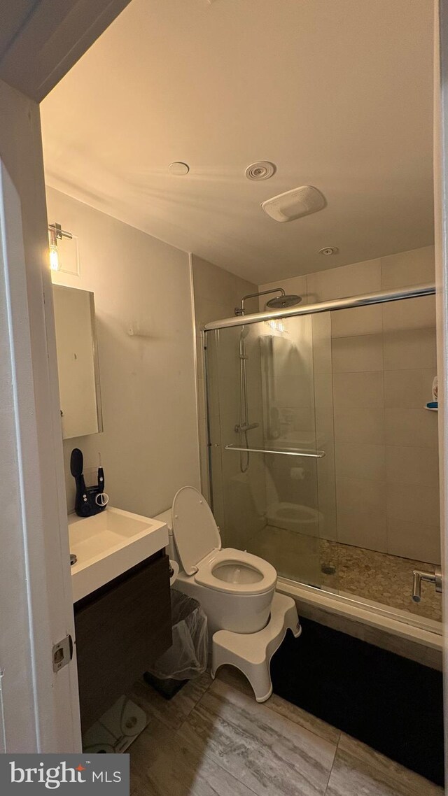 full bathroom featuring toilet, a stall shower, wood finished floors, and vanity