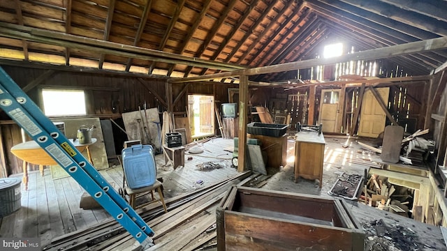 misc room featuring vaulted ceiling and wooden walls